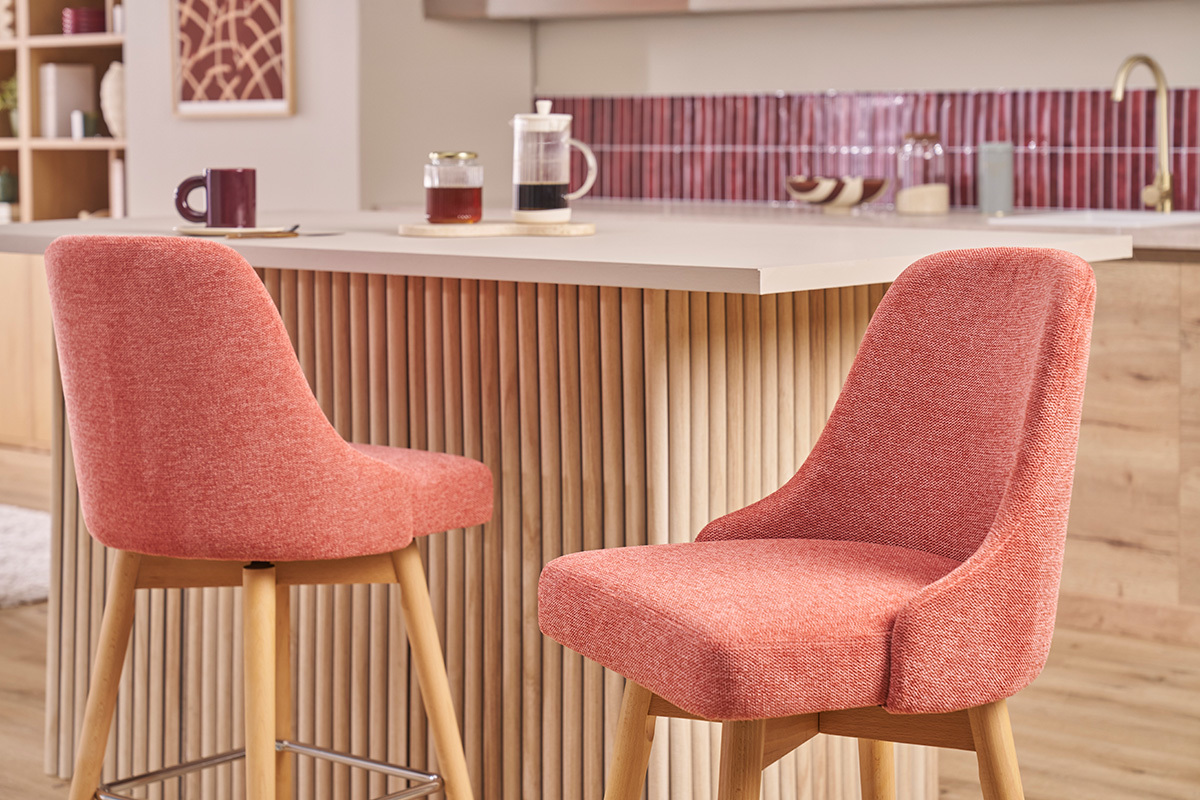 Taburetes de bar escandinavos de tela terracota y madera frente a un mostrador.