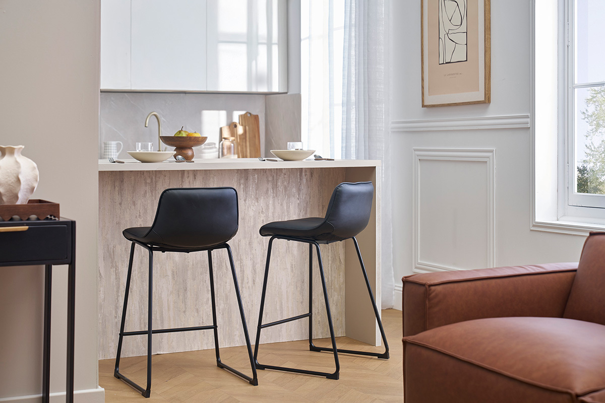 Dos taburetes de bar negros y metlicos de 65 cm frente a un mostrador de cocina.