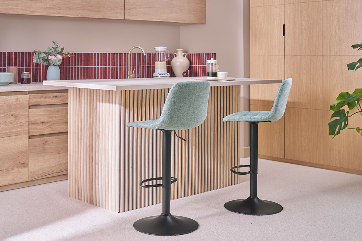 Taburetes ajustables de celad�n y metal frente a una encimera de cocina de madera.