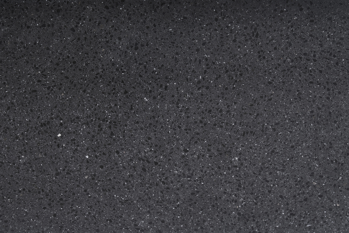 Lavabo cuadrado de terrazo negro, vista de cerca, con textura mineral y matices variados.